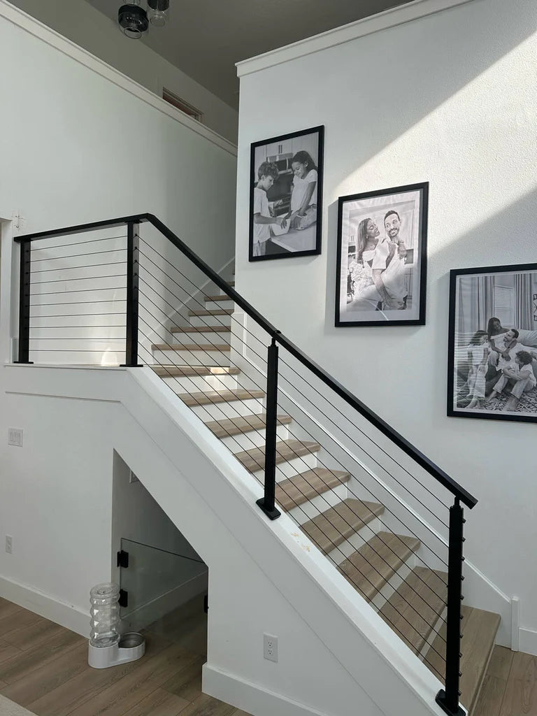 Staircase with black cable railing, metal balusters, and framed pictures on the wall